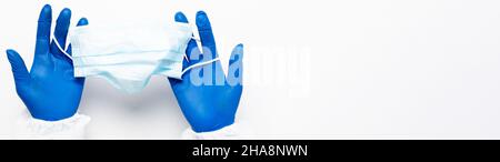 Main du médecin dans des gants médicaux bleus tient le masque anti-virus sur fond blanc pour la pandémie, les maladies aéroportées, épidémie, Covid19 concept. Banque D'Images