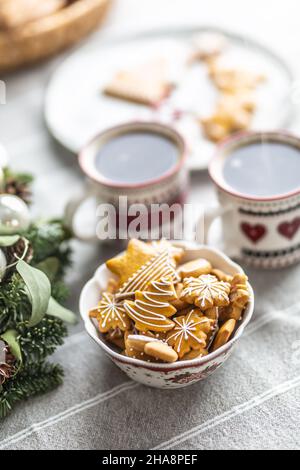 Un bol rempli de pain d'épice de Noël sur la table a mené une couronne de l'Avent et deux tasses avec café, punch ou thé. Banque D'Images