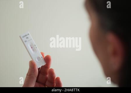 le visage d'une femme floue montre un test rapide positif de covid-19 Banque D'Images