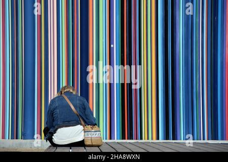 Une femme se reposant devant un artsort de l'artiste Raymond Moretti à la Défense, le quartier des affaires de Paris.L'œuvre est une collection de pailles géantes Banque D'Images