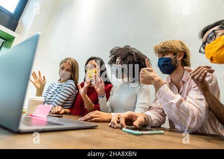Conférence vidéo de l'équipe des étudiants, réunion avec masque facial en raison du virus Covid-19 et corona, appel vidéo en alibrary, jeunes avec masque facial utilisant le lapt Banque D'Images