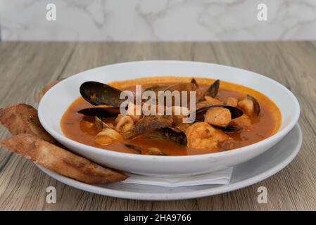 Grand bol de fruits de mer et poisson-coquille cioppino plein de calamars tranchés, moules, et palourdes dans une soupe généreuse. Banque D'Images