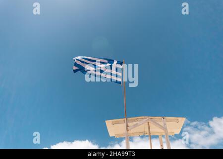 Drapeau grec sur la plage sur fond bleu ciel. Banque D'Images
