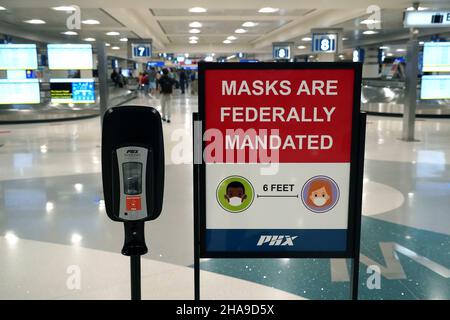 Un panneau d'avertissement de mandat de masque fédéral et un distributeur de désinfectant pour les mains dans la zone de retrait des bagages du terminal 4 de l'aéroport international de Sky Harbor, Tuesda Banque D'Images