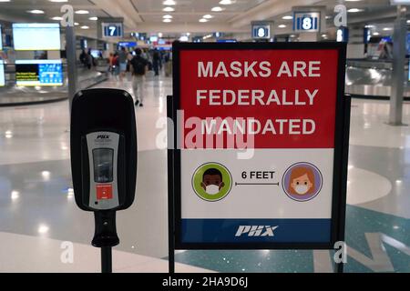 Un panneau d'avertissement de mandat de masque fédéral et un distributeur de désinfectant pour les mains dans la zone de retrait des bagages du terminal 4 de l'aéroport international de Sky Harbor, Tuesda Banque D'Images