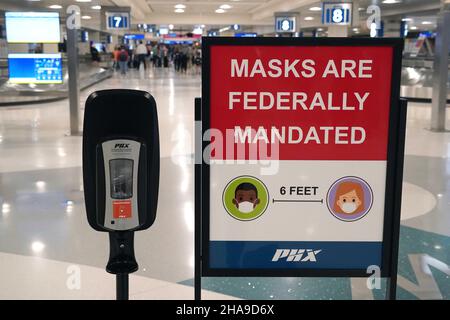 Un panneau d'avertissement de mandat de masque fédéral et un distributeur de désinfectant pour les mains dans la zone de retrait des bagages du terminal 4 de l'aéroport international de Sky Harbor, Tuesda Banque D'Images