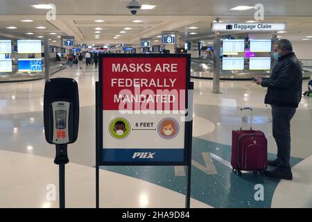 Un panneau d'avertissement de mandat de masque fédéral et un distributeur de désinfectant pour les mains dans la zone de retrait des bagages du terminal 4 de l'aéroport international de Sky Harbor, Tuesda Banque D'Images