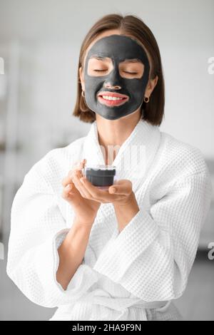 Jeune femme avec un masque de charbon activé sur son visage à la maison Banque D'Images