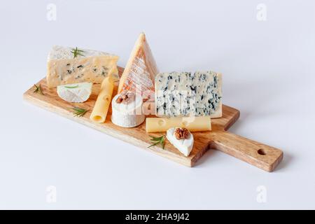 différents types de fromage sur une planche à découper sur fond blanc Banque D'Images