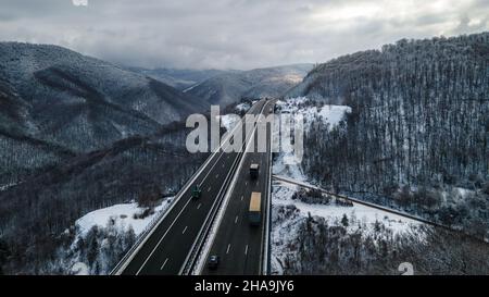 Vue aérienne incroyable sur une route.Superbe paysage de neige avec rivière et arbres.Voitures roulant sur la route.Tir de drone de neige.Photo de haute qualité Banque D'Images