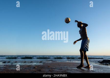 Salvador, Bahia, Brésil - 08 janvier 2020 : jeune homme qualifié jouant au football sur sable au coucher du soleil sur la plage d'Ondina à Salvador, Bahia, Brésil. Banque D'Images