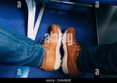 Pieds mâles en baskets brunes sur un tapis bleu.Gros plan Banque D'Images