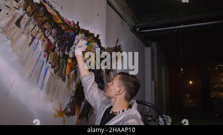 Concepteur de l'artiste dessine un aigle sur le mur. Décorateur artisan photo peintures à l'acrylique couleur d'huile. Peintre peintre vêtu de couche de peinture. À l'intérieur. Banque D'Images