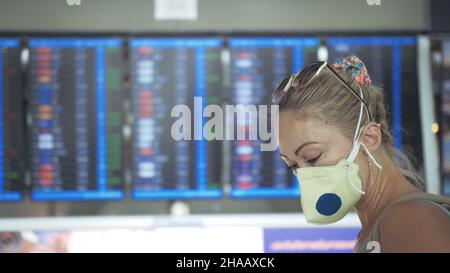 Femme caucasienne à l'aéroport de Suvarnabhumi avec masque médical protecteur. Carte d'information de vol. Coronavirus sars-cov-2 covid-19. Banque D'Images