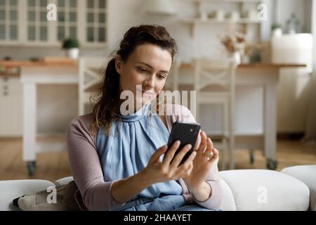 Une femme positive qui utilise une application de commerce électronique virtuelle sur un téléphone mobile Banque D'Images