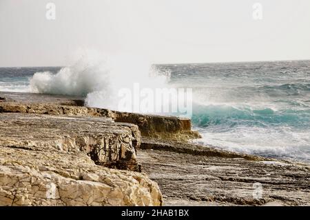 Une grande vague éclabousse sur la plage rocheuse croate pendant un fort vent sur la mer Adriatique.Ligne d'horizon. Banque D'Images