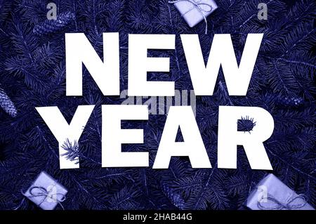 Mots nouvel an sur les branches de sapin vert avec de petits boxes-cadeaux colorés dans la couleur tendance de l'année 2022 très Peri. Banque D'Images