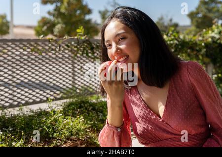 femme souriante posant un jour ensoleillé avec une pomme dans sa main avant de la manger, portrait horizontal Banque D'Images