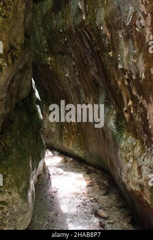 Vue à l'intérieur de la grotte avec des rayons de lumière et de petites pierres dans une eau peu profonde Banque D'Images