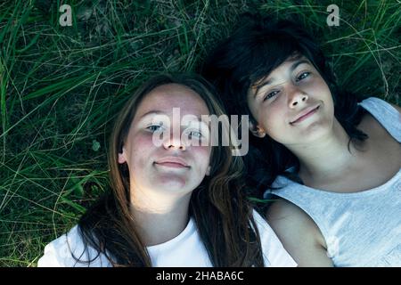 Portrait du dessus des deux filles allongé sur l'herbe verte. Banque D'Images