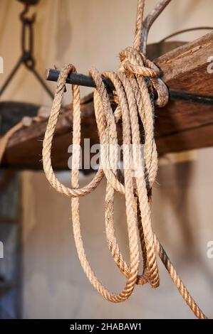 Détail d'une ancienne corde de chanvre accrochée à une barre de fer et une étagère en bois Banque D'Images