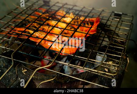 Crevettes grillées sur un grill au charbon de bois.Des crevettes géantes d'eau douce grillent sur un feu de charbon de bois flamboyant.Gros plan sur la cuisson de crevettes géantes sur le grille-barbecue. Banque D'Images