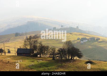 Paysage d'automne dans un village de montagne.Vieilles maisons en bois sur les collines.Lumière du soleil avec brouillard Banque D'Images