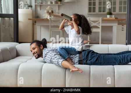 Une fille africaine assis sur le dos de papa regarde dans les tubes de papier Banque D'Images