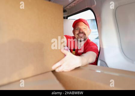 Homme appréciant de travailler en compagnie de livraison, mettre des boîtes dans le camion pour une livraison ultérieure à l'adresse Banque D'Images