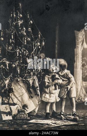 Petits enfants avec arbre de Noël, cadeaux et jouets vintage.Image ancienne avec film original Banque D'Images