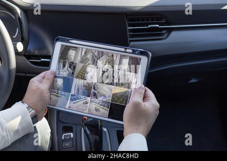 Homme surveillant des caméras cctv sur une tablette numérique en voiture Banque D'Images