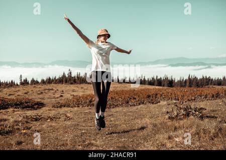 Les touristes féminins sautent dans la nature.Magnifique paysage des Carpates bannière avec des collines, des nuages et de la forêt à l'aube à l'automne Banque D'Images