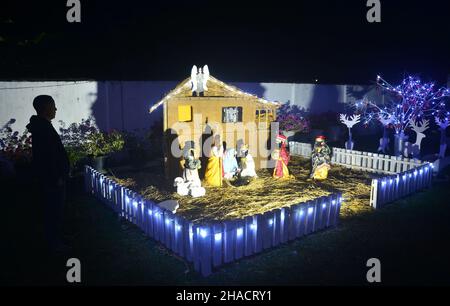 Dimapur, Inde.12th décembre 2021.Les piétons indiens admirent la décoration de la Nativitrie de Jésus exposée devant l'église baptiste de Mao, alors qu'elle est éclairée avant le festival de Noël à Dimapur, dans l'État du Nagaland, au nord-est de l'Inde.Credit: Caisii Mao/Alay Live News Banque D'Images