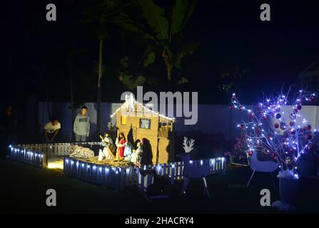 Dimapur, Inde.12th décembre 2021.Les piétons indiens admirent la décoration de la Nativiterie de Jésus exposée devant l'église baptiste de Mao, alors qu'elle est éclairée avant le festival de Noël à Dimapur, dans l'État du Nagaland, au nord-est de l'Inde.Credit: Caisii Mao/Alay Live News Banque D'Images