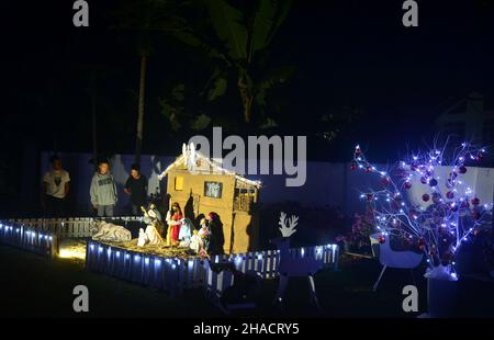 Dimapur, Inde.12th décembre 2021.Les piétons indiens admirent la décoration de la Nativiterie de Jésus exposée devant l'église baptiste de Mao, alors qu'elle est éclairée avant le festival de Noël à Dimapur, dans l'État du Nagaland, au nord-est de l'Inde.Credit: Caisii Mao/Alay Live News Banque D'Images