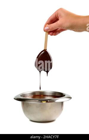 Trempez à la main de la glace à la vanille en forme de coeur sur un bâton de bois dans du chocolat noir liquide chaud Banque D'Images