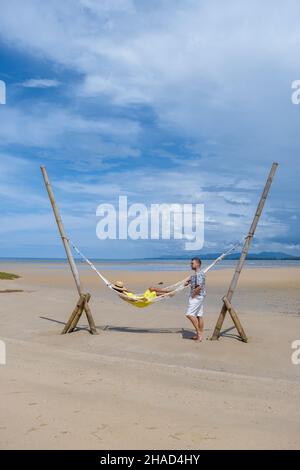 Couple homme et femmes se détendant dans un hamac sur la plage de Phuket Nai yang plage Thaïlande. Ciel bleu avec un hamac sur la plage Banque D'Images