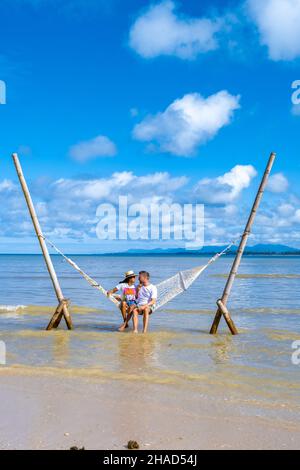 Couple homme et femmes se détendant dans un hamac sur la plage de Phuket Nai yang plage Thaïlande. Ciel bleu avec un hamac sur la plage Banque D'Images