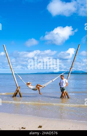 Couple homme et femmes se détendant dans un hamac sur la plage de Phuket Nai yang plage Thaïlande. Ciel bleu avec un hamac sur la plage Banque D'Images