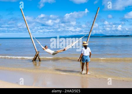 Couple homme et femmes se détendant dans un hamac sur la plage de Phuket Nai yang plage Thaïlande. Ciel bleu avec un hamac sur la plage Banque D'Images
