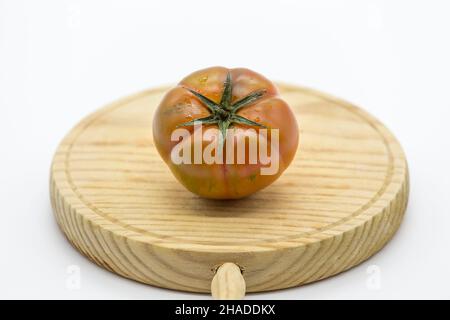 tomate de type raf placée sur un panneau en bois sur fond blanc Banque D'Images