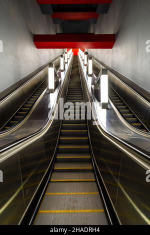 Marches d'un escalier roulant long allant jusqu'aux dalles rouges sur le plafond.Perspective linéaire.Image verticale. Banque D'Images