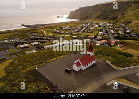 Vue aérienne de l'église de Vik dans le sud de l'Islande, vue sur la mer avec les célèbres formations rocheuses en arrière-plan Banque D'Images