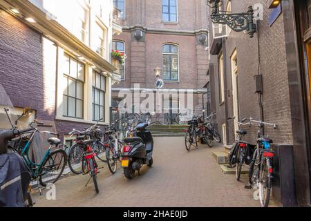 Pays-Bas.Journée ensoleillée à Amsterdam.Petite rue latérale avec des vélos et des scooters Banque D'Images