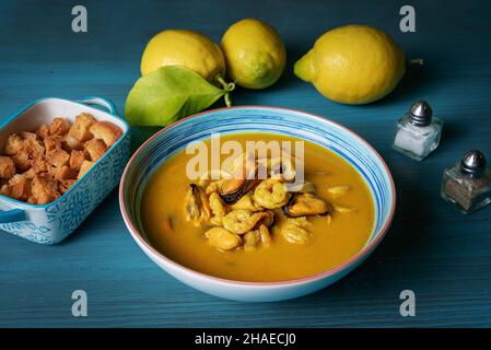 Soupe de fruits de mer à base de crevettes, moules, palourdes, merlu et calmar,servi avec du pain frit et des citrons. Banque D'Images