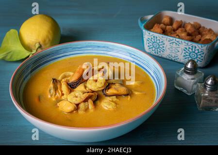 Soupe de fruits de mer à base de crevettes, moules, palourdes, merlu et calmar,servi avec du pain frit et des citrons. Banque D'Images