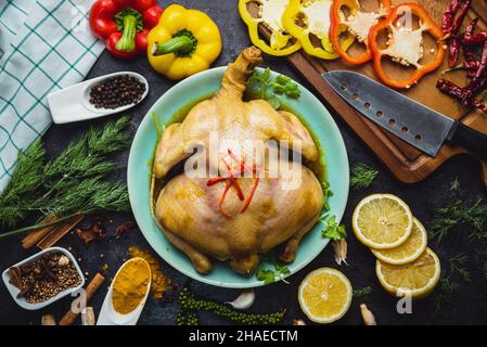 Vue de dessus de poulet entier avec citron et légumes divers sur la table.Poulet rôti entier sur l'assiette.Placement alimentaire de fond et divers Banque D'Images