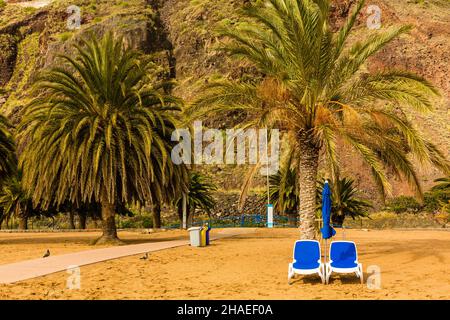 Reposez-vous sur la mer Méditerranée.Deux chaises longues bleues sont installées sur une verrière ensoleillée près des palmiers.Nature tropicale dans une station balnéaire.Le concept de Banque D'Images