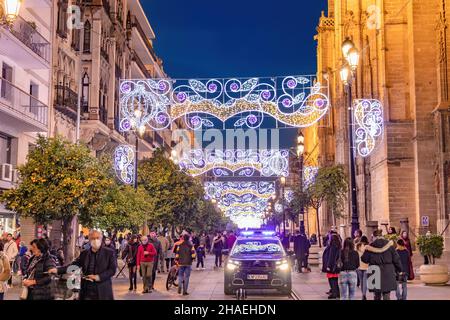 Noël lumières décoration dans l'avenue Constitution, Avenida de la Constitución, à Séville, avec une voiture de police patrouilant pour assurer la sécurité de la p Banque D'Images