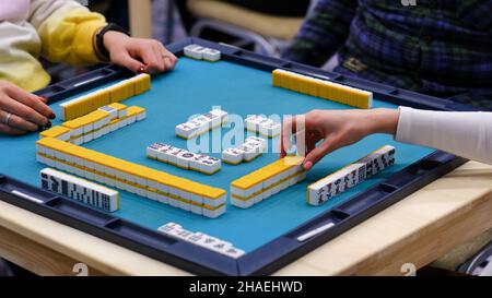 Une table de mahjong avec un jeu actif et les mains des participants au jeu.Un jeu asiatique ancien appelé Mahjong comme un moyen de se détendre et d'avoir du plaisir Banque D'Images